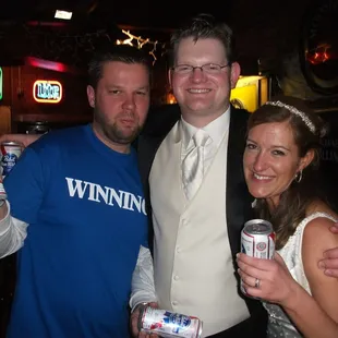 two men and a woman holding cans of beer