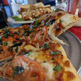a person taking a slice of pizza