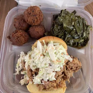 Pulled pork sandwich with coleslaw, collard and hush puppy sides.