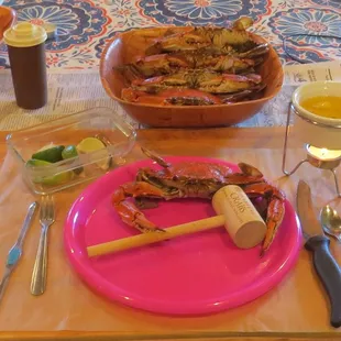 a pink plate with a knife, fork, and glass of wine