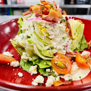 wedge of crisp iceberg lettuce, hickory bacon, bleu cheese crumbles, tomatoes, red onions, bleu cheese dressing