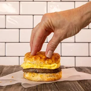 a hand reaching for a breakfast sandwich