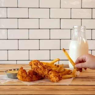 a person holding a glass of milk and fries