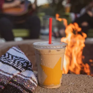 a cup of iced coffee next to a fire pit