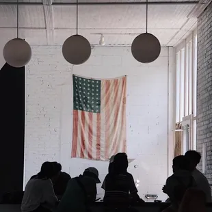 a group of people sitting at a table in front of an american flag