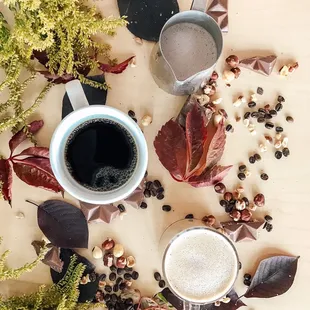 a cup of coffee surrounded by leaves and berries