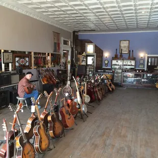 A customer tries out a nice classical guitar among the various guitars in the front room.