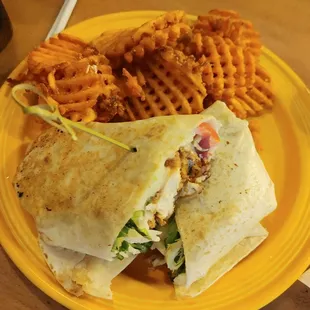 a yellow plate with a sandwich and waffle fries