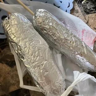 two hot dogs wrapped in tin foil