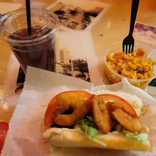 Shrimp Po&apos;Boy (half eaten) w/ Mac and Cheese and lemonade Iced tea.