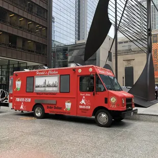 a red food truck parked in front of a building