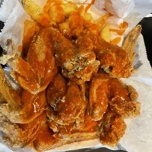 Fried chicken wing and fries with hot sauce on top