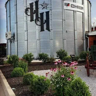 a silo with flowers in the foreground