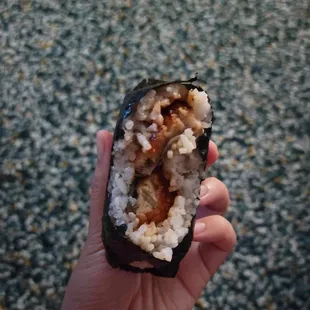 a hand holding a piece of sushi