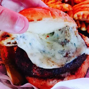 a hand grabbing a cheeseburger