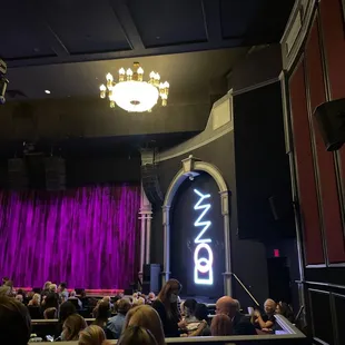 a stage with a chandelier and purple drapes