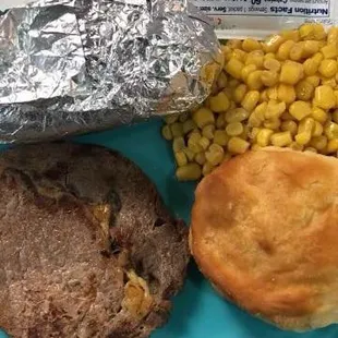 a plate of food including corn, biscuits, and a biscuit