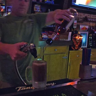 The bartender demonstrates the typical pour of their drinks.
