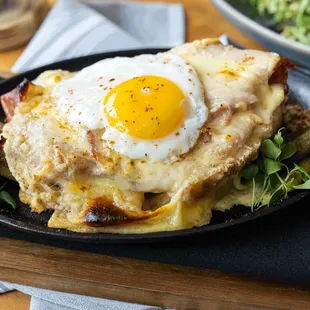 Oven Baked Croque Madame Skillet: artisanal bread, Jambon de Paris, Raclette cheese, white wine, egg, cornichons, grain mustard