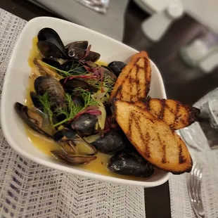 a plate of musselling and bread on a table