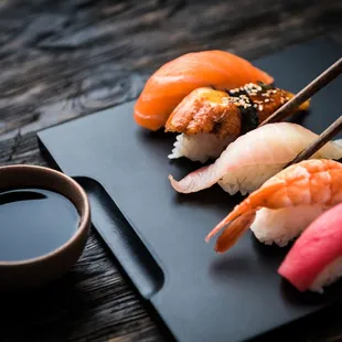 a closeup of a plate of sushi with chopsticks