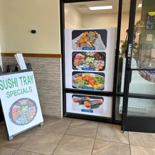 a sushi tray specials sign in front of a door