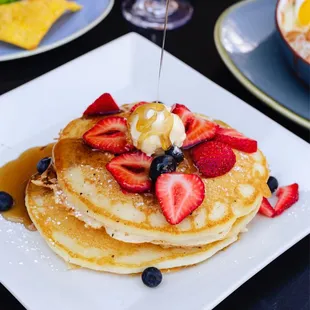 a plate of pancakes with strawberries and blueberries