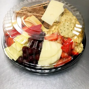 a plate of cheese, crackers, fruit, and crackers