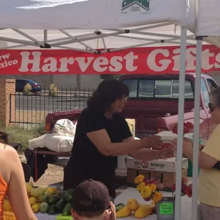 a woman handing a box of fruit to a child