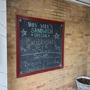 a chalkboard on the side of a brick building
