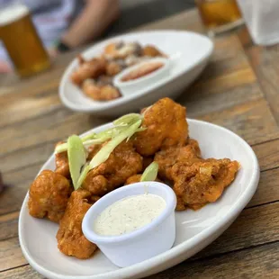 a plate of fried chicken wings with avocado and ranch dip