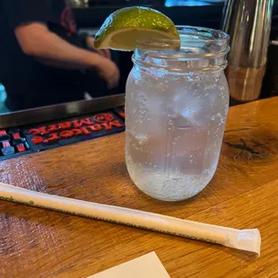 a drink in a mason jar with a lime wedge