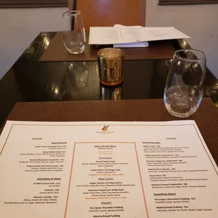 a menu and wine glasses on a table