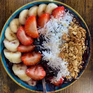 Acai bowl with coconut, blueberries, strawberries, bananas, granola and honey.