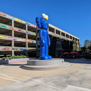 Statue, parking structure and outdoor seating with orange umbrellas