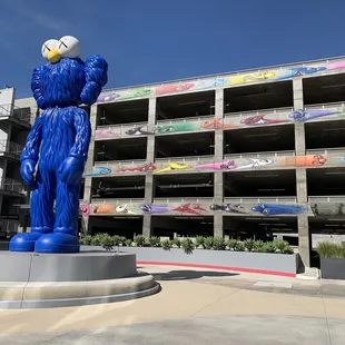 a blue statue of a man holding a soccer ball in front of a parking garage