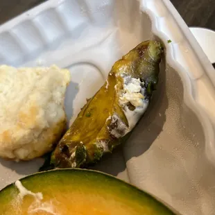 a pickle and a biscuit on a styrofoam container