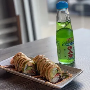 a plate of sushi rolls and a bottle of soda