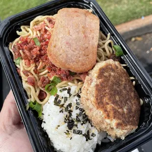 a hand holding a container of hashi and rice