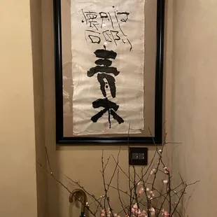 a vase of flowers in front of a japanese scroll