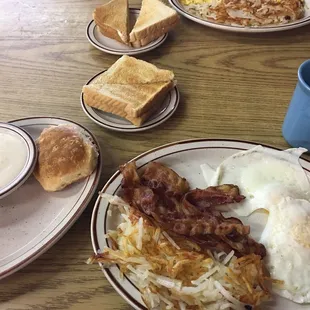 a breakfast of eggs, bacon, hash browns, and bread