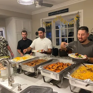 a group of people standing around a buffet