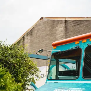 a blue truck with orange trim parked in front of a building