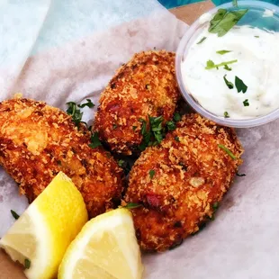 a plate of fried fish with lemon wedges