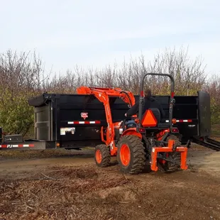 Loading our dump trailer with wood chips with our Kubota tractor that we use on larger jobs.