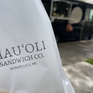 a hand holding a bag of sandwiches