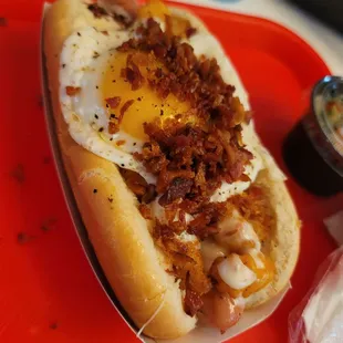 a hot dog with bacon and an egg