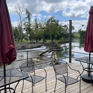 tables and chairs on a deck overlooking a river