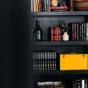 a black bookcase with books and baskets