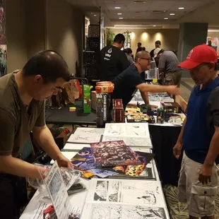 Comic book artist Walden Wong signing prints.